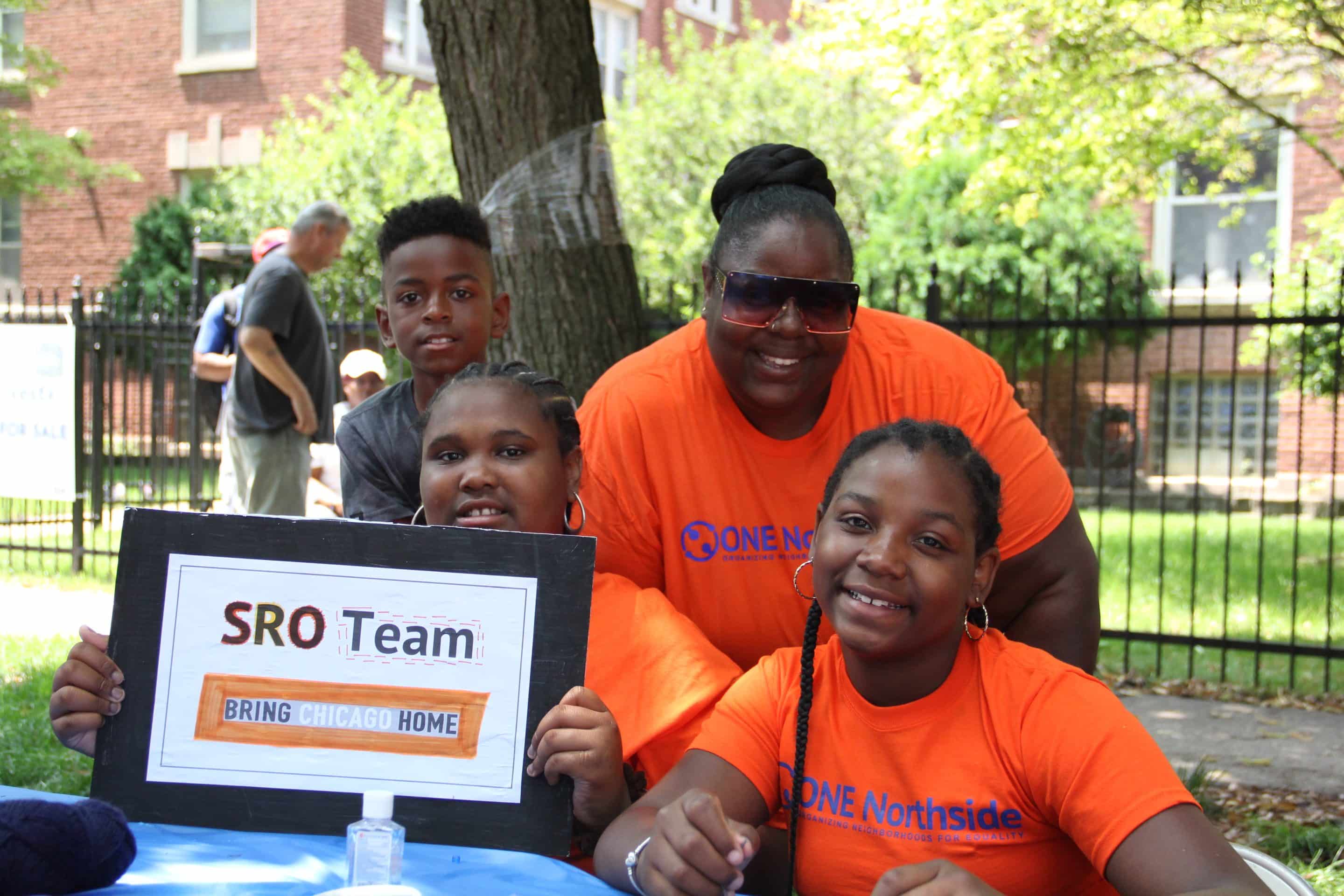 a smiling family in orange shirts with a sign that says SRO team