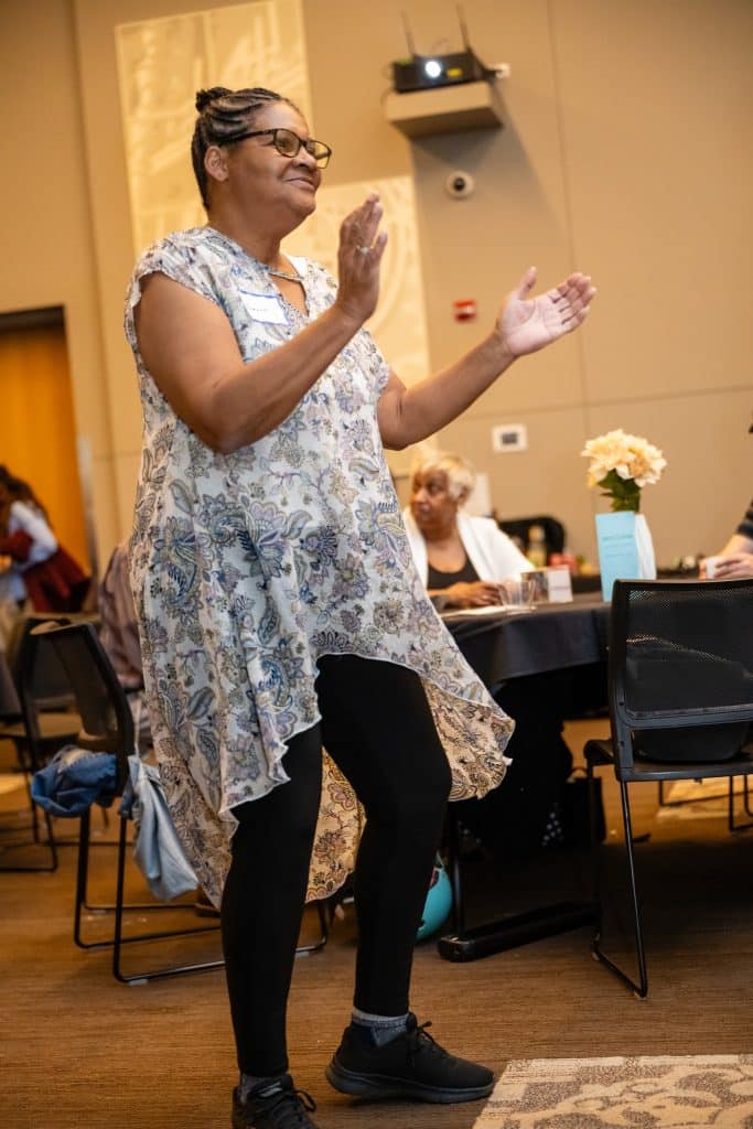A woman dances as people talk in the background.