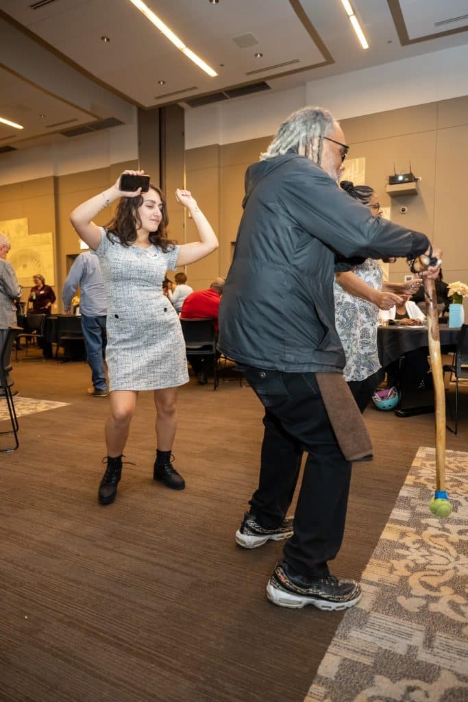 People dance while others in the background chat.