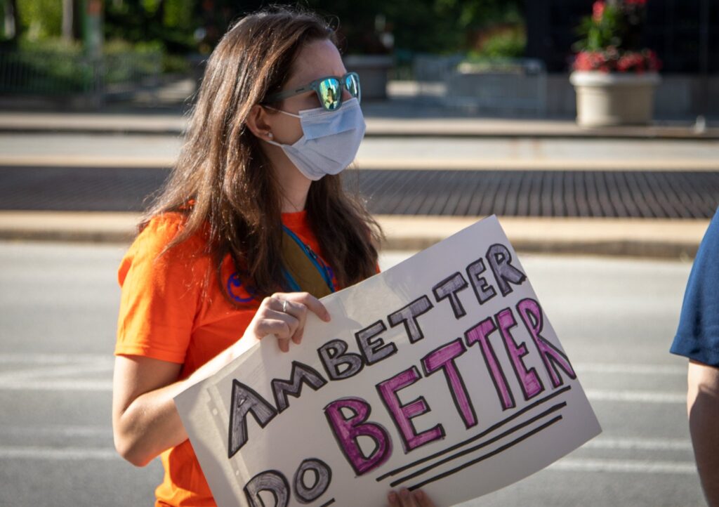 a woman holding a sign saying ambetter do better