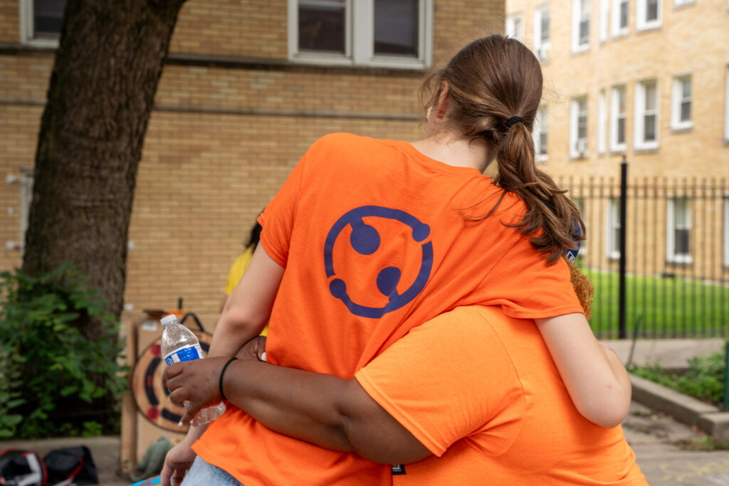Two people in ONE Northside t-shirts sharing a hug